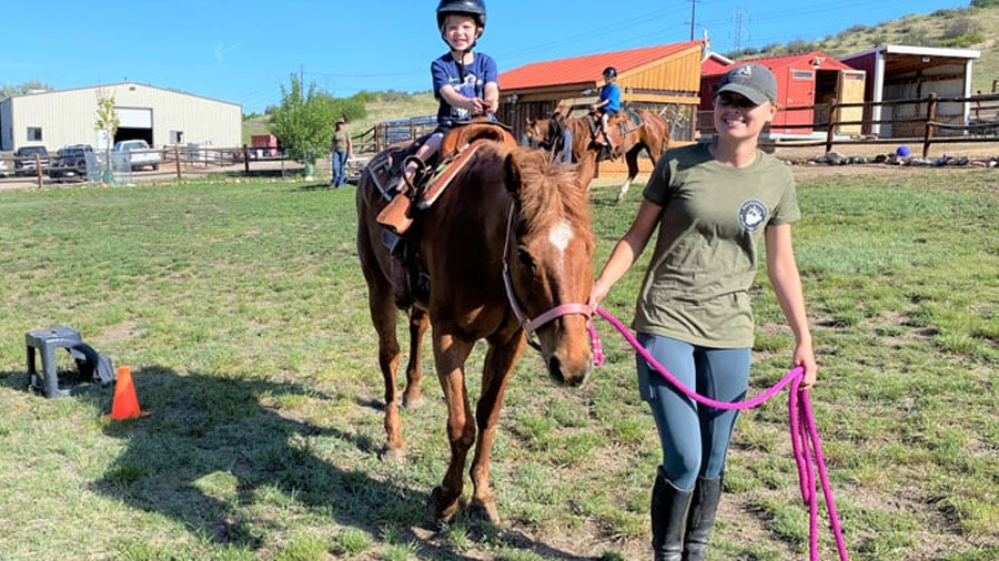 Child on pony being led around by a young adult